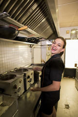 Young woman working in old kitchen smiling and cooking