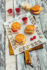 Sweet cake in the form of a burger, strawberry mousse with white chocolate and roll with sesame seeds, cooking background