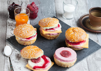 Obraz na płótnie Canvas Sweet cake in the form of a burger, strawberry mousse with white chocolate and roll with sesame seeds, cooking background