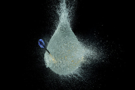 Balloon filled with water is popped with dart to make a mess