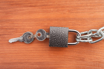 Metal chain links and lock on wooden background