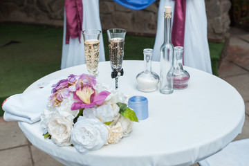 Table with glasses and a bouquet of flowers for the wedding ceremony