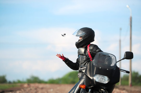 Fototapeta The charming girl in a black helmet sits on the motorcycle and t