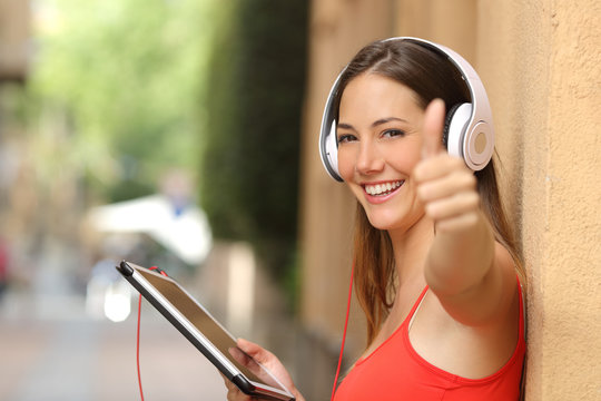 Girl with thumbs up using a tablet with headphones