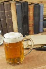 Cool glass of beer on the table. Relax with a good book with a glass of cold beer. The concept relax with a good beer. Pouring a glass of beer for readers of the book. Alcohol and study.
