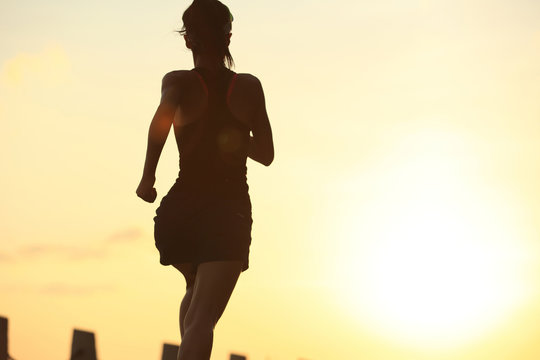 young fitness woman running on sunrise seaside trail