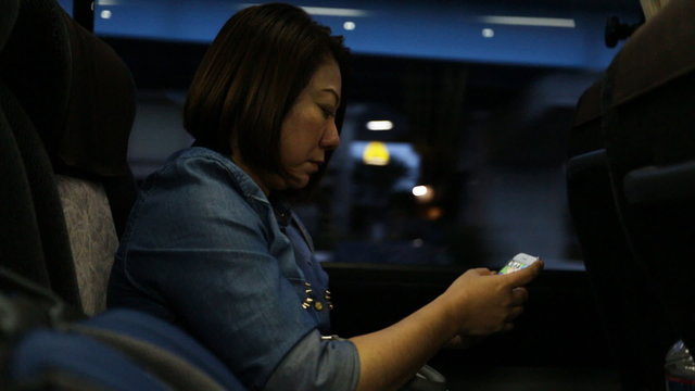 Asian woman using smartphone while riding bus
