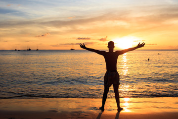 Fototapeta na wymiar African men raising arms up at Sunset in Tarrafal beach in San
