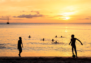 Obraz premium Childrens silhouette playing soccer on sunset at Tarrafal beach