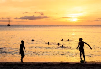 Zelfklevend Fotobehang Childrens silhouette playing soccer on sunset at Tarrafal beach © Samuel B.