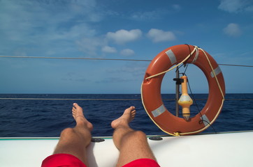 Beine hochlegen auf einem Katamaran im Urlaub während eines Ausflugs.