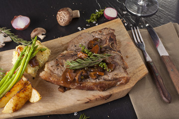 T-bone steak, a prepared piece of grilled T-bone steak brown sauce with mashed potato and vegetable on dining table decorated
