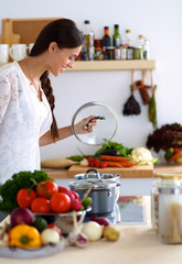 Young woman standing by the stove in the kitchen