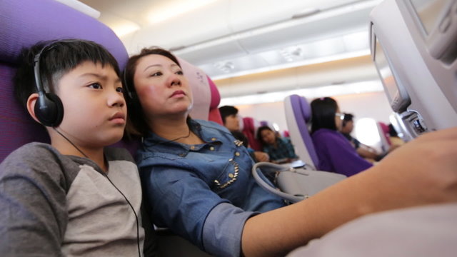 happy asian family playing and watching monitor on air plane