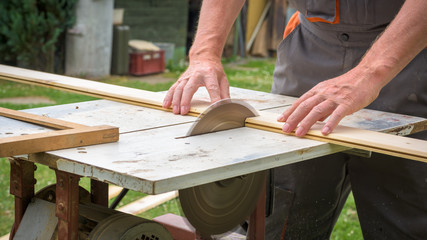 Carpenter working with electric buzz saw cutting wooden boards