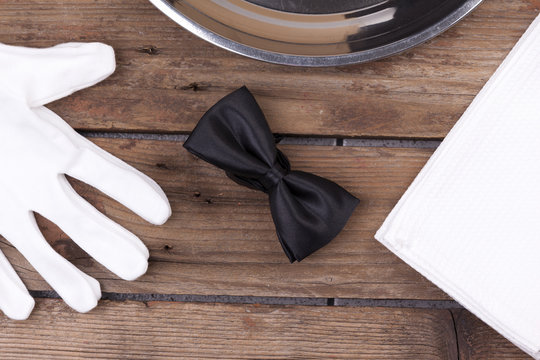 Top View Of A Waiter Tray, Bow Tie, Gloves And A Napkin On Woode