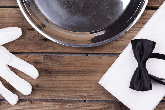 Top View Of A Waiter Tray, Bow Tie, Gloves And A Napkin On Woode