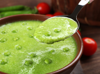 Tasty peas soup and cherry tomatoes on table close up
