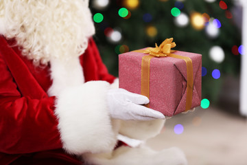 Santa holding gift on Christmas tree background