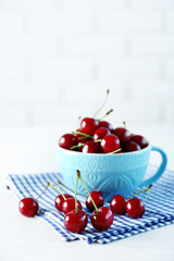 Cherries in mug on table, on light background
