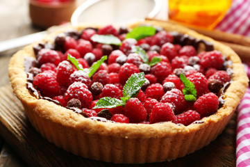 Tart with fresh raspberries, on wooden background