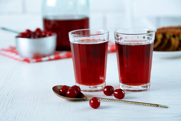 Sweet homemade cherry juice on table, on light background