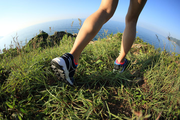 woman hiker legs hiking on seaside mountain grass
