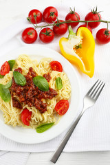 Spaghetti Bolognese on white plate, on color wooden background