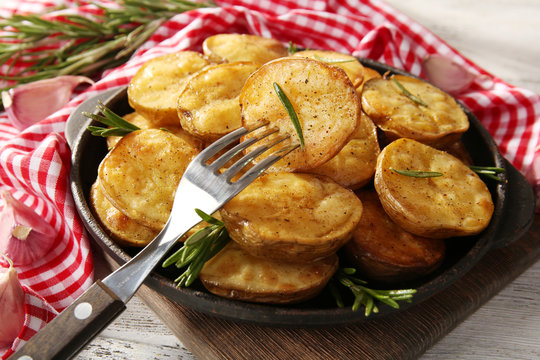 Delicious baked potato with rosemary in frying pan on table close up