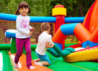 Fototapeta na wymiar happy kids having fun on inflatable attraction playground