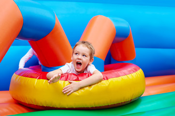 happy excited boy having fun on inflatable attraction playground
