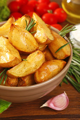 Baked potato wedges on wooden table, closeup