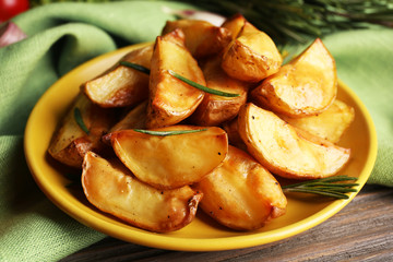 Baked potato wedges on wooden table, closeup
