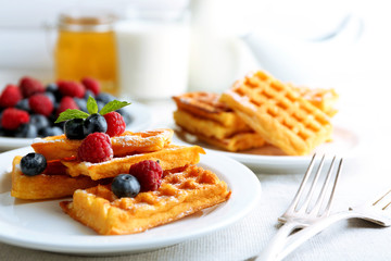 Sweet homemade waffles with forest berries and sauce on table background