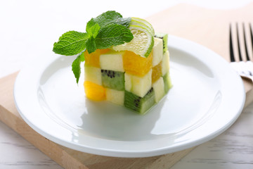 Fruit salad on plate, on light wooden background
