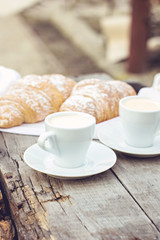A cup of coffee "espresso" and croissant on the wooden table.