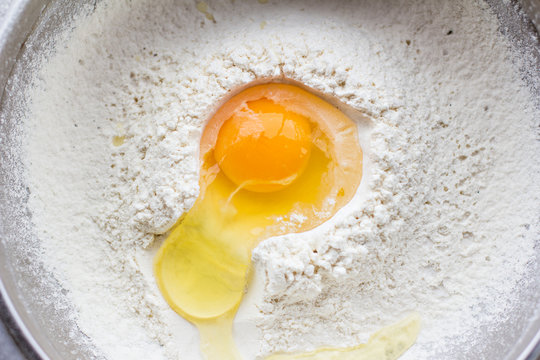 raw egg broken into flour