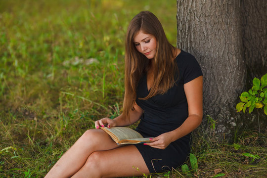 woman girl reading a book under a tree sitting nature summer edu