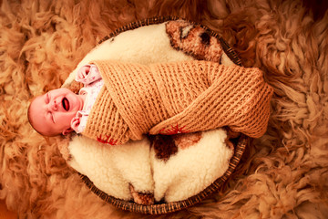Fototapeta na wymiar newborn baby covered in knitted scarf cries
