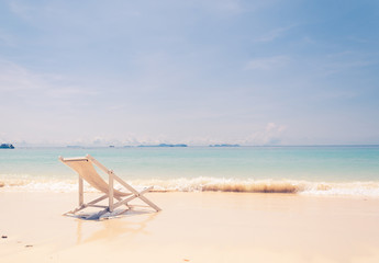 Fototapeta na wymiar beach chair on beach with blue sky - soft focus with film filter