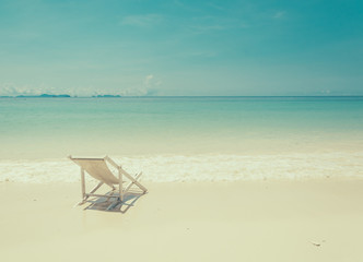 Fototapeta na wymiar beach chair on beach with blue sky - soft focus with film filter