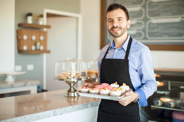 Business owner greeting customers and selling cupcakes in a bakery shop