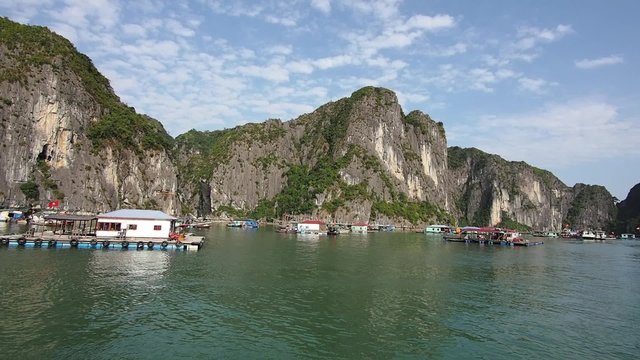 View of floating fishing village and limestone cliffs in Halong Bay, Vietnam.
