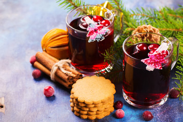 Obraz na płótnie Canvas Hot xmas punch with spices and cranberry in glass cups and ginger cookies. Christmas or new year background with decorations. Selective focus