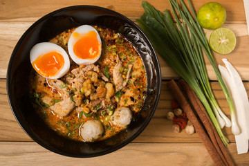 bowl of noodles with vegetables and soft boiled egg on wooden ta