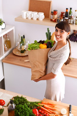 Young woman holding grocery shopping bag with vegetables