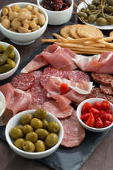 Assorted deli meat snacks, sausages and pickles on a blackboard