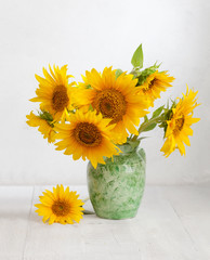 Naklejka premium Bouquet of sunflowers in old ceramic jug on wooden table.