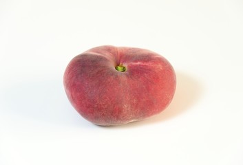 A whole, medium-size, ripe, juicy saturn peach shaped like a donut with a sunken middle, white skin with red blush isolated on background. An oddly doughnut like flat round peach yet tasty.