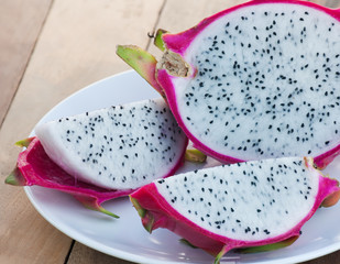 Dragon fruit on white plates on wooden floors, seasonal fruits with reddish bark.